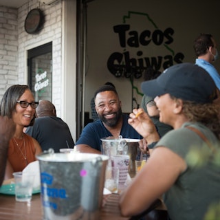 a group of friends enjoying conversation and tacos on the patio at Tacos Chiwas